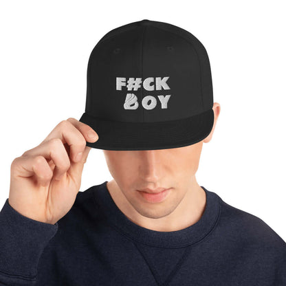 Man wearing black snapback cap with text "F#CK BOY" on the front, adjusting the brim.
