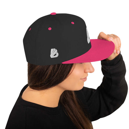 Side view of Snapback-Cap N°1 in black and pink with structured 6-panel design, worn by a woman.