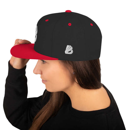 Woman wearing Snapback-Cap N°1 with red visor and black crown, showcasing high-profile structured design and adjustable snap closure.