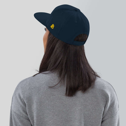 Woman wearing Snapback-Cap N°4 with curved visor and structured design, featuring adjustable snap closure and embroidered eyelets.