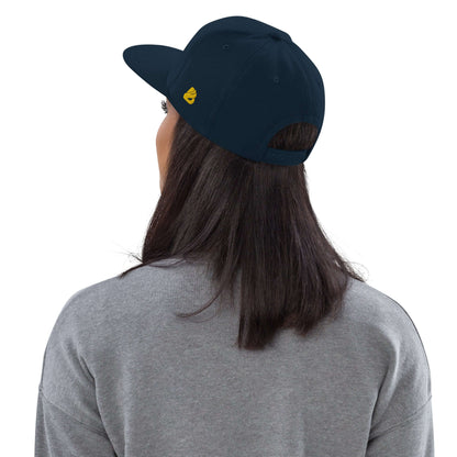 Person wearing Snapback-Cap N°4, showing back view with navy color and yellow logo embroidered, featuring adjustable snap closure.