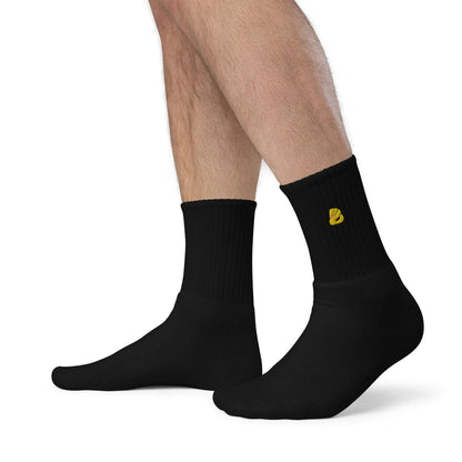 Man wearing Bestickte Socken N°0, black embroidered socks with yellow logo, showcasing quality and comfort.