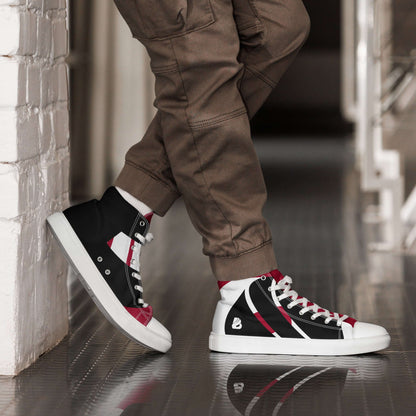 Person wearing stylish High-Top Leinenschuhe für Herren N°4 with black and red accents, leaning against a wall indoors.
