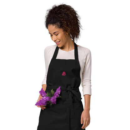 Woman wearing Schürze aus Bio-Baumwolle N°0 in kitchen holding purple flowers.