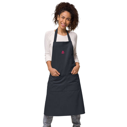 Person wearing Schürze aus Bio-Baumwolle N°0, a stylish black apron with adjustable straps and front pockets, made from 100% organic cotton.