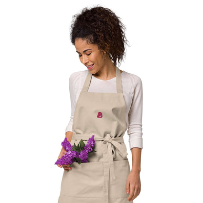 Person wearing Schürze aus Bio-Baumwolle N°0 holding purple flowers, highlighting adjustable straps and large front pocket.