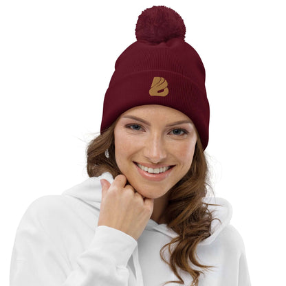 Woman wearing Bommel-Beanie N°0 in burgundy with matching pom-pom and logo, 100% soft acrylic fiber, perfect for fall and winter.