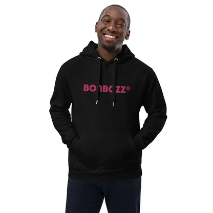 Smiling person wearing black hoodie with pink 'BOMBZZZ' logo, showcasing a relaxed fit.
