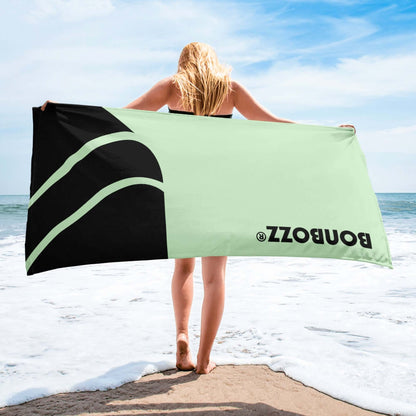 Woman holding Handtuch N°0 on beach, showcasing soft, vibrant towel with ocean background, ideal for enhancing bathroom decor.