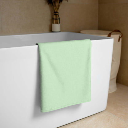 Handtuch N°0 in soft green draped over bathtub, highlighting super-soft and absorbent towel material. Ideal for vibrant bathroom decor.