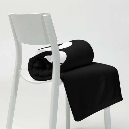 Black and white Tagesdecke draped over a modern white chair, showcasing its soft silken texture and stylish design.