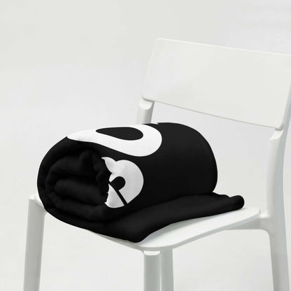 Black and white Tagesdecke folded on a white chair, showcasing soft, hypoallergenic polyester fabric, ideal for stylish home decor.