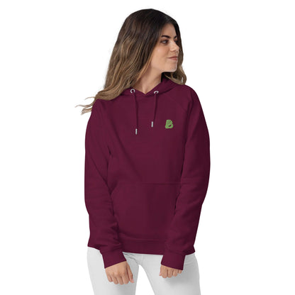 Woman wearing burgundy Unisex Bio-Raglan-Hoodie N°0, showcasing comfort and style with logo detail on front.