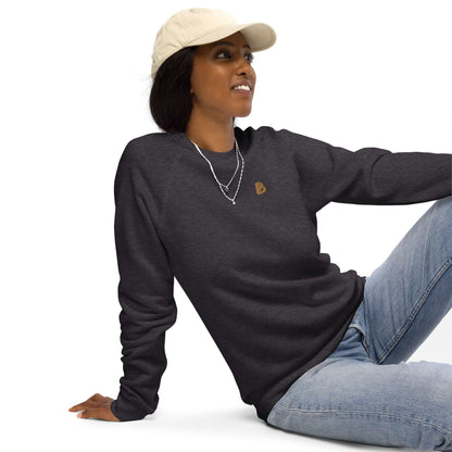 Woman wearing a Unisex Bio-Raglan-Pullover N°0 in charcoal, paired with a cap and necklace, sitting casually.
