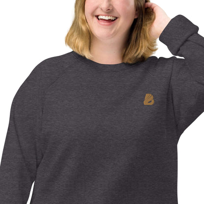 Woman wearing Unisex Bio-Raglan-Pullover N°0 with brushed fleece interior and 100% cotton exterior, smiling comfortably.