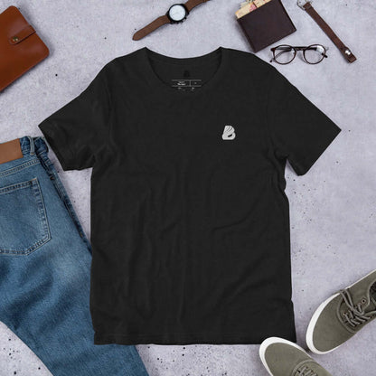Kurzärmeliges Unisex-T-Shirt N°1 in schwarz, aus 100 % gekämmter und ringgesponnener Baumwolle, auf grauem Hintergrund arrangiert mit Accessoires.